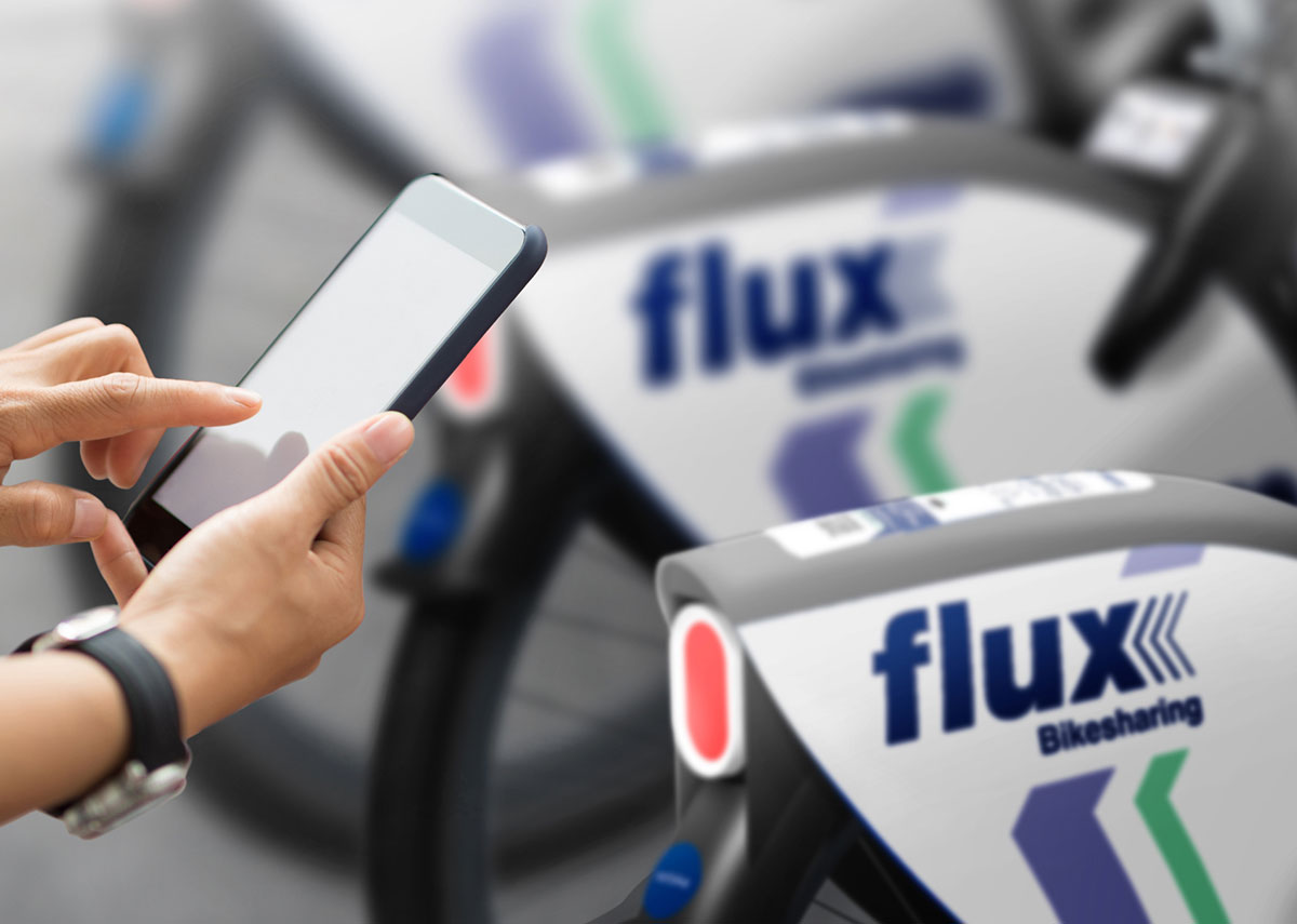 Ein Handy mit Smartphone vor Fahrrädern mit dem Logo von "Flux"